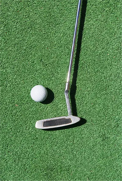 white golf ball and putter lying on putting green grass