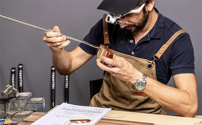 Man working on Trentini putter by hand with magnifier at workshop desk